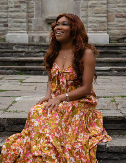 A woman in a floral dress sits on steps.